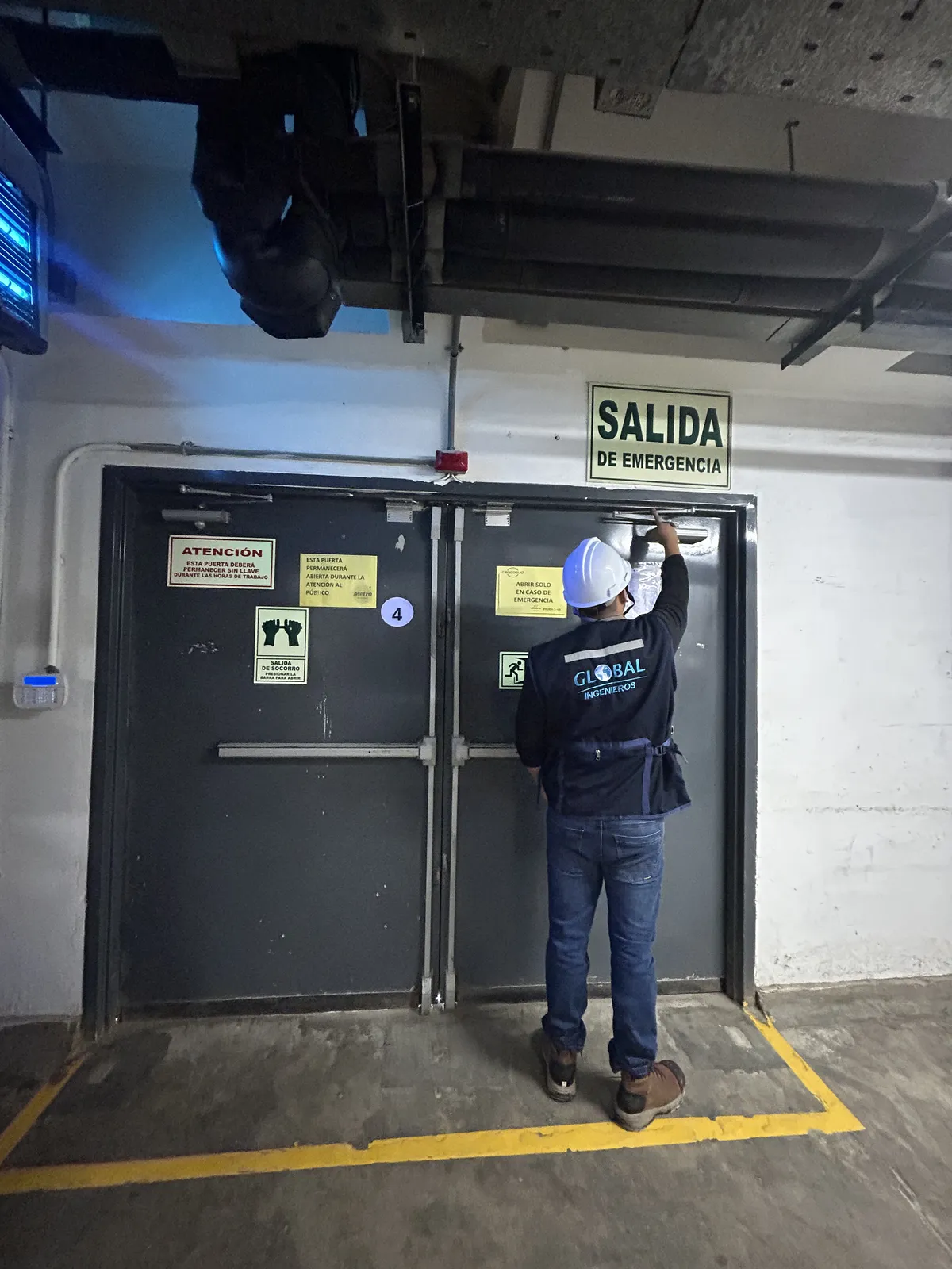 Ingeniero de Global Ingenieros probando el cierre de una puerta cortafuego de salida de emergencia