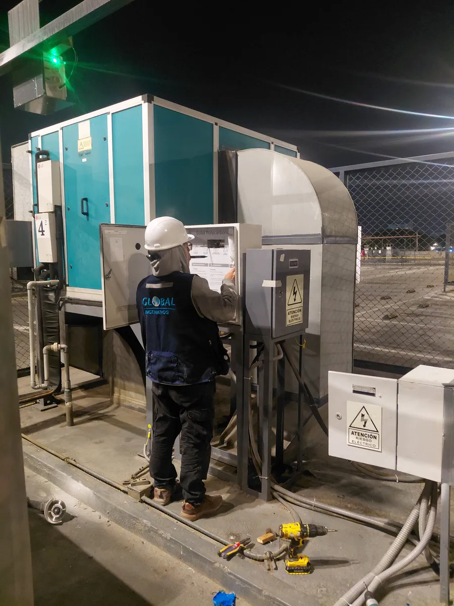 Técnico de Global Ingenieros trabajando en un tablero eléctrico, con señalización de riesgo eléctrico