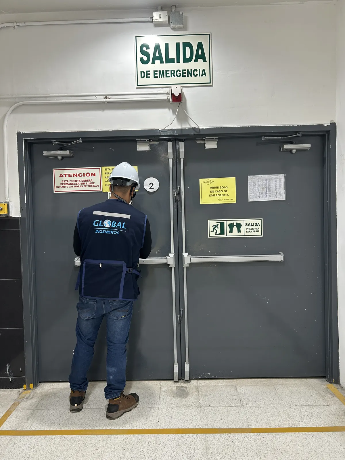 Ingeniero de Global Ingenieros probando una puerta de salida de emergencia con barra antipánico durante una inspección